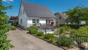 Une maison à deux étages dotée d’un balcon, d’une allée pavée et d’un jardin bien entretenu.