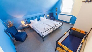 Une chambre à coucher avec un lit, une chaise, une petite table et une fenêtre.