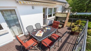 Une terrasse extérieure avec une table et des chaises, un barbecue et une vue sur une maison.
