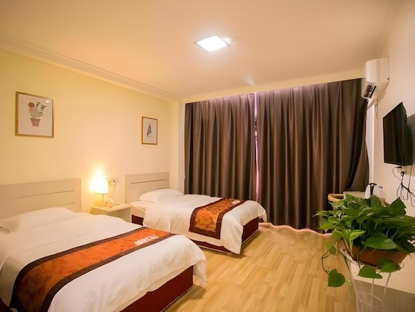 Habitación de hotel con dos camas, un ventanal con cortinas, un televisor de pantalla plana y una planta en maceta.