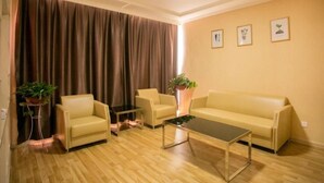 Un salon comprenant un canapé, deux fauteuils, une table basse et une grande fenêtre avec des rideaux.