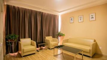 A living room with a sofa, two armchairs, a coffee table, and a large window with curtains.