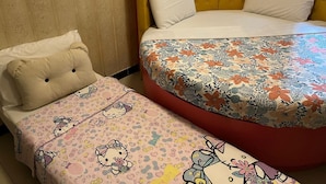 Una habitación con dos camas, una con una colcha estampada de flores y la otra con motivos de Hello Kitty.