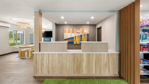 A reception area with a wooden reception desk, a large abstract painting, and a view of the outside. - Casco Bay Inn (Freeport)