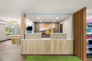 A reception area with a wooden reception desk, a large abstract painting, and a view of the outside. - Casco Bay Inn (Freeport)