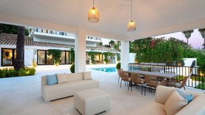A modern outdoor living space with a pool, seating area, and a dining table. - Vrbo Property (Marbella)