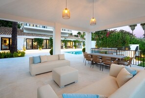 Ein moderner Außenbereich mit Pool, Sitzgelegenheit und Esstisch.