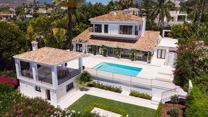 A two-story house with a swimming pool, surrounded by lush greenery and palm trees. - Vrbo Property (Marbella)