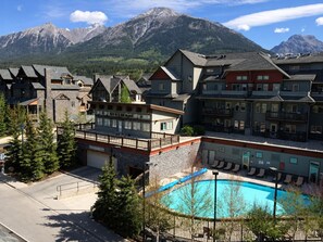 Ett semesterområde med en pool, flera byggnader och berg i bakgrunden.
