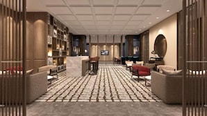 Eine moderne Hotelhalle mit Rezeption, Sitzbereich und einem Fernsehbildschirm.