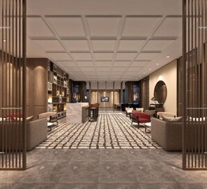 Eine moderne Hotelhalle mit Rezeption, Sitzbereich und einem Fernsehbildschirm.