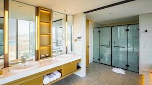 Ein modernes Badezimmer mit zwei Waschbecken, einem großen Spiegel und einer Glasdusche.