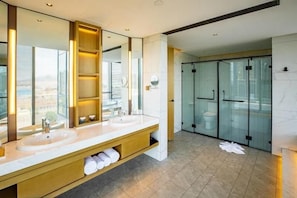 Ein modernes Badezimmer mit zwei Waschbecken, einem großen Spiegel und einer Glasdusche.