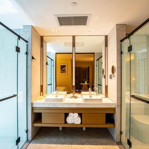 Ein modernes Badezimmer mit zwei Waschbecken, einem großen Spiegel und einer Duschkabine.