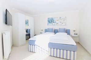 A bedroom with a bed, a television, a mirror, and artwork on the wall. - Holiday apartment with 2 bedrooms (Zingst)