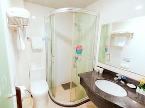 Ein modernes Badezimmer mit einer Duschkabine, einer weißen Toilette und einem Marmorwaschtisch mit Spiegel.