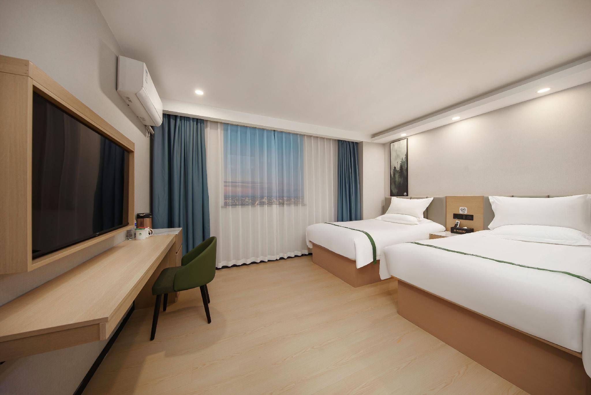 A hotel room with a bed, a desk, a chair, a TV, and a window with curtains.