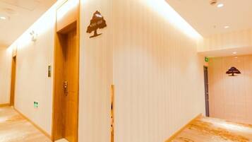 A hotel corridor with wooden doors, a reception area, and a sign indicating a room number.