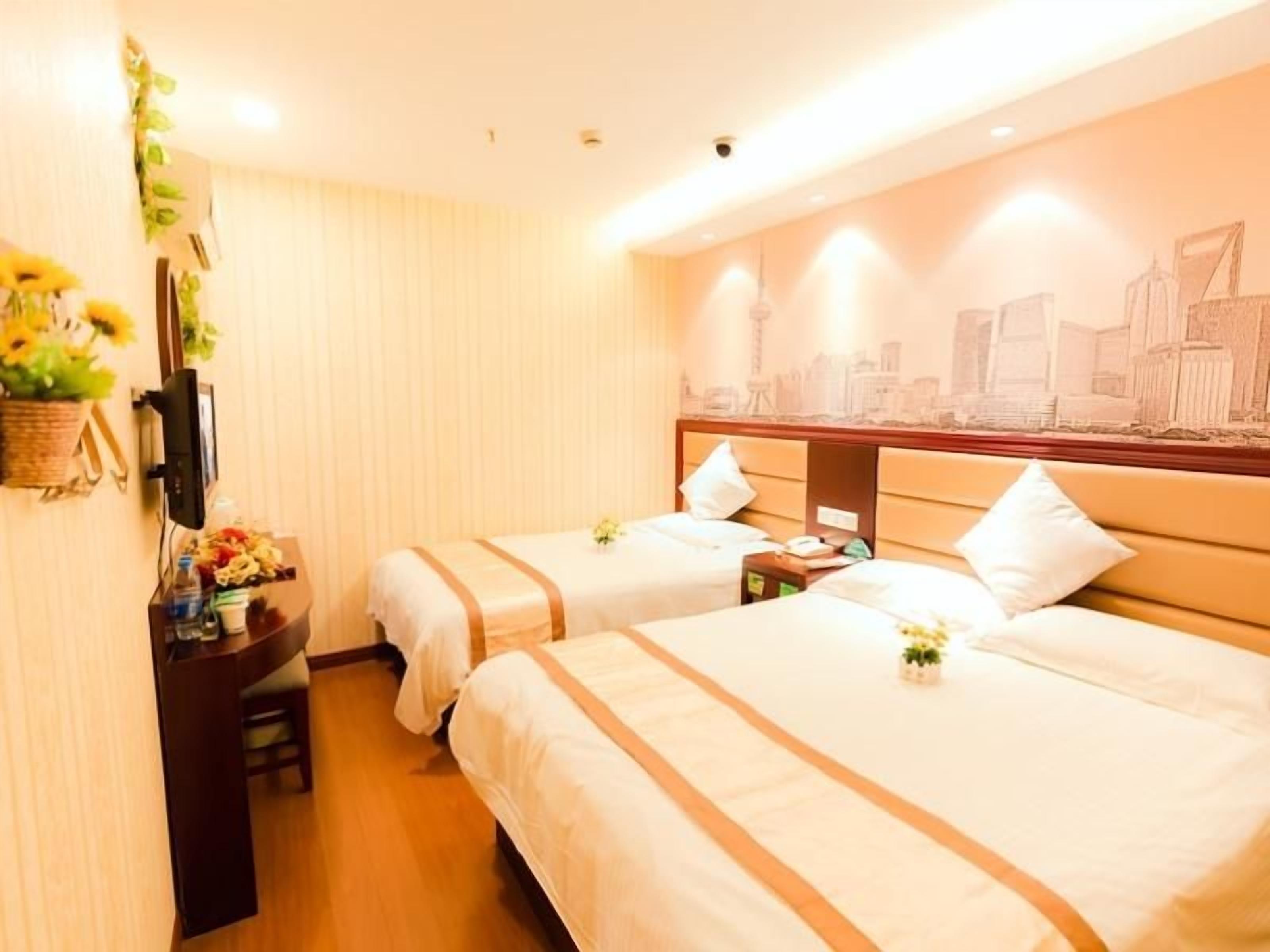 A hotel room with two beds, a desk with a computer, a TV, and a wall mural.