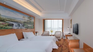 A hotel room with two beds, a desk, a chair, a TV, and a large window with curtains. - Vienna International Hotel (Langfang)