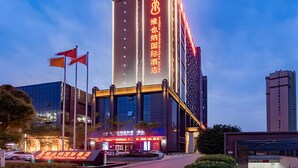 A modern hotel building with illuminated signage, a prominent vertical sign, and a well-lit entrance. - Vienna International Hotel (Huanggang)