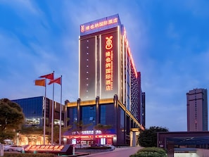 Edifici d'hotel modern amb cartelleria il·luminada, un senyal vertical destacat i una entrada ben il·luminada.