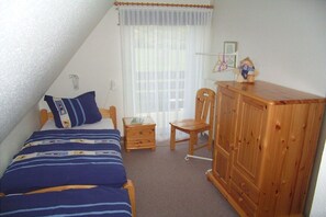 Ein Schlafzimmer mit einem Bett, einem Holzschrank, einem Sessel und einem kleinen Tisch.