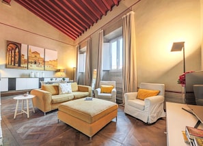 A modern living room with a sofa, armchair, ottoman, and a small table.