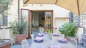 An outdoor dining area with a table set for four, surrounded by potted plants and white chairs. - Luxury Apartment in Central Florence (Florence)