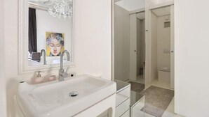 A modern bathroom with a white sink, a large mirror, and a chandelier. - Luxury Apartment in Central Florence (Florence)
