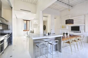 A modern kitchen with a central island, bar stools, and a dining area.