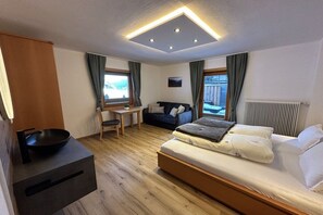 A modern bedroom with a bed, a desk, and a view of the outdoors. - Holiday apartment with 1 bedroom (St. Jakob)
