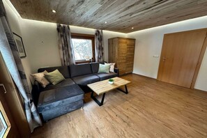A modern living room with a sectional sofa, a wooden coffee table, and a wardrobe. - Holiday apartment with 1 bedroom (St. Jakob)
