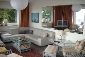 Ein Wohnzimmer mit einer Couch, Sesseln, einem Couchtisch und einem Fernseher.