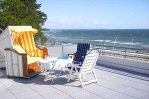 Ein Balkon mit Meerblick, ausgestattet mit zwei Stühlen und einem kleinen Tisch.