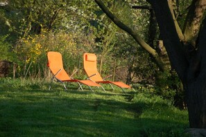 Two orange lounge chairs in a grassy outdoor area with trees and foliage in the background. - Old Rectory Elmenhorst (Elmenhorst)