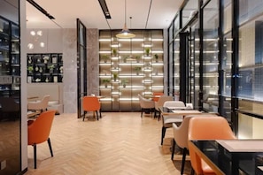 A modern interior with a herringbone floor, orange chairs, and a wall-mounted plant display. - Echarm Hotel (Mianyang)