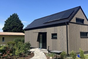 Ein modernes Gebäude mit Satteldach, einer sichtbaren Tür und einem kleinen Fenster.