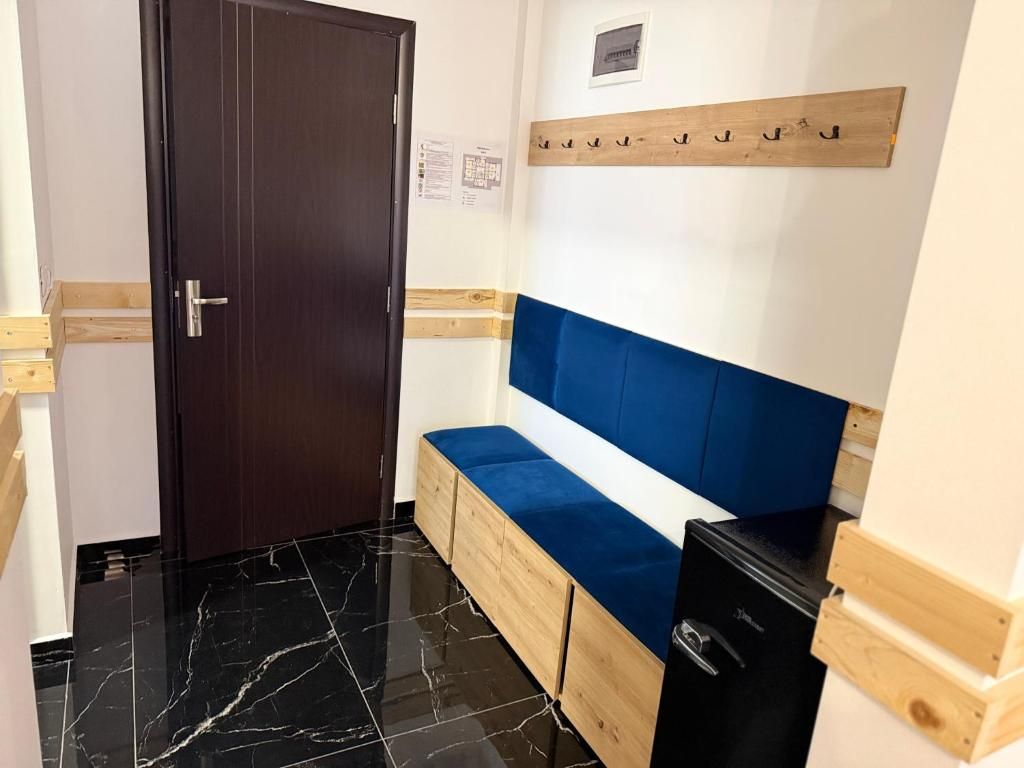 Ein Zimmer mit einer dunkelholzigen Tür, einer blauen gepolsterten Bank, einem Holzanziehgestell und einem schwarzen Gerät.