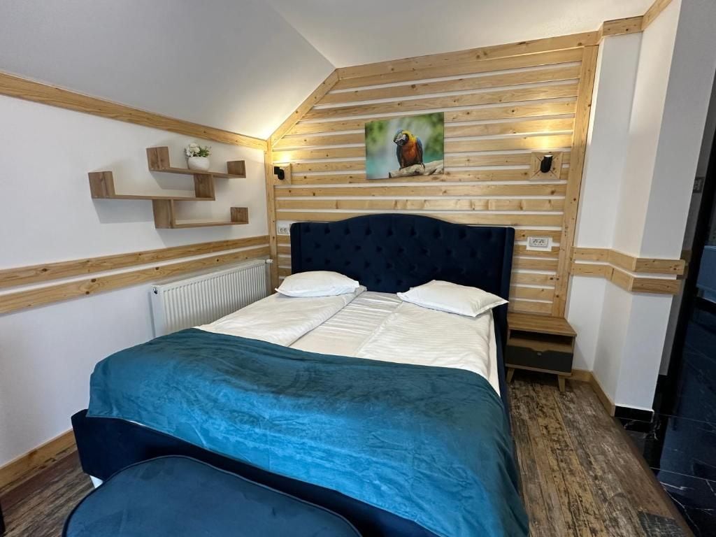 Ein Schlafzimmer mit einem Bett, einem Kopfteil, einer Holzvertäfelung, einem Gemälde und einem kleinen Regal.