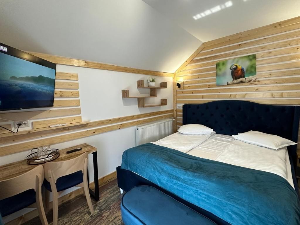 Une chambre à coucher avec un lit, un téléviseur fixé au mur, des étagères en bois et un tableau.