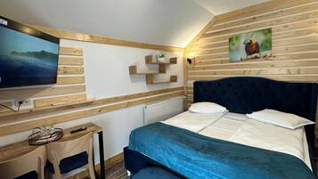 Une chambre à coucher avec un lit, un téléviseur fixé au mur, des étagères en bois et un tableau.