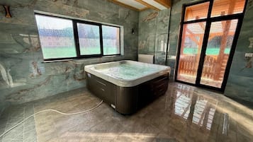A room with a large hot tub, a window with a view, and a door with a view.