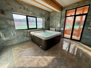 Una habitación con un jacuzzi grande, un ventanal con vistas y una puerta con vistas.