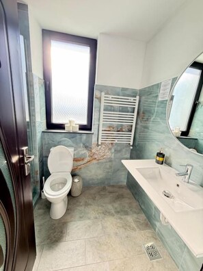Ein Badezimmer mit Toilette, Waschbecken und einem Fenster.