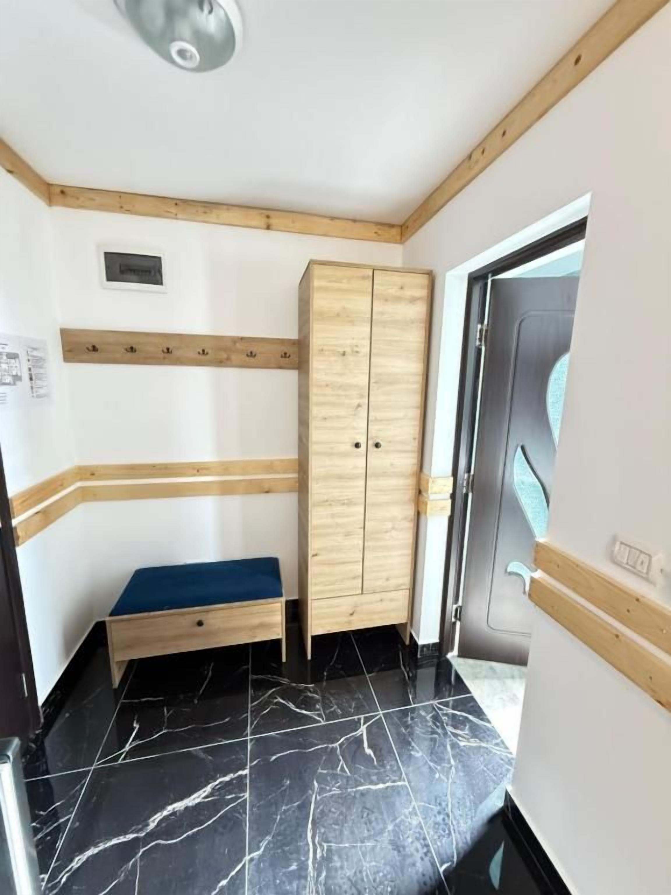 Una stanza con un armadio in legno, una panca e una porta che dà sull'esterno.