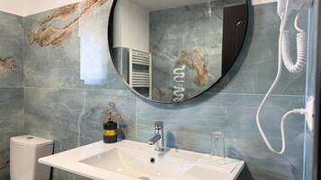 A bathroom with a white sink, a round mirror, and a toilet.