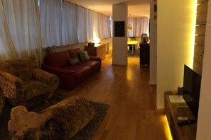 Ein Wohnzimmer mit einem roten Sofa, einem Holztisch und einem Fernseher.