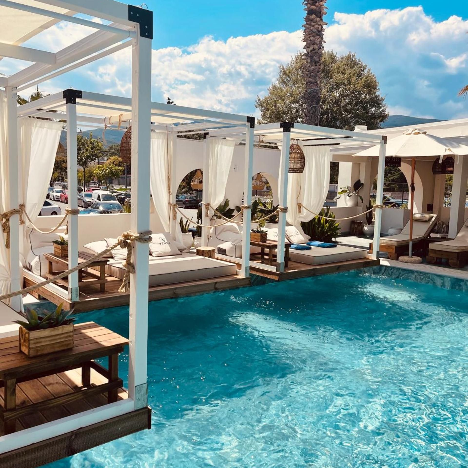 A poolside area with cabanas, lounge chairs, and a clear blue pool.