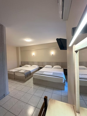 Hotellihuone, jossa on kaksi sänkyä, työpöytä ja peili.